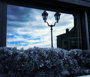 Snow covered street light against cloudy sky