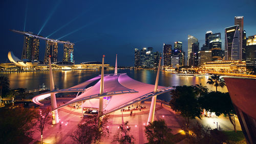 Illuminated modern buildings in city against sky at night