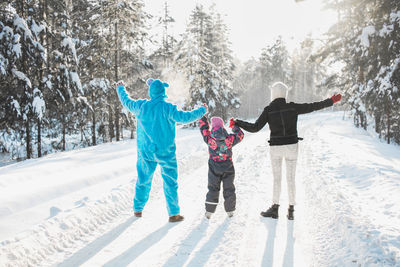 Rear view of friends standing on snow covered trees