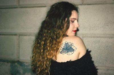 Woman looking away while standing against wall