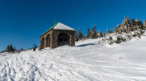 Snow covered building against clear blue sky