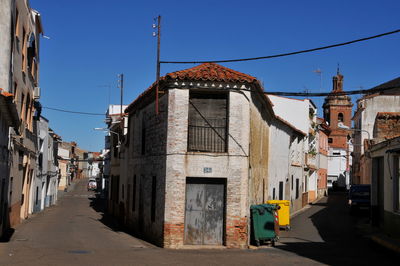 Street amidst buildings in city against clear blue sky