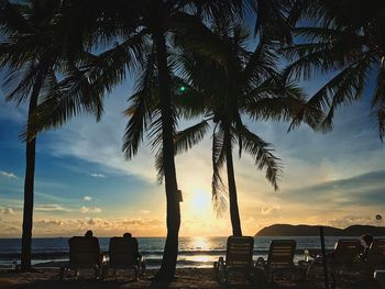Silhouette palm trees on beach against sky at sunset