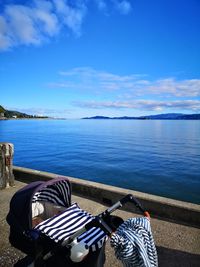 Deck chairs by sea against blue sky