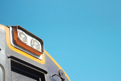 Low angle view of yellow truck against clear blue sky