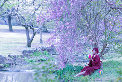 Woman holding ball while sitting on field at park