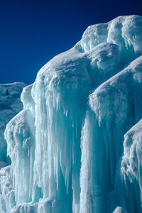 Snow covered landscape against clear blue sky