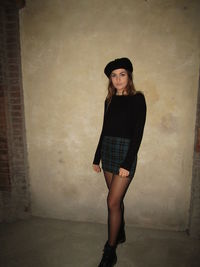 Portrait of woman standing against wall