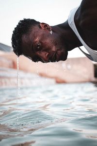 Portrait of young man washing head in pond