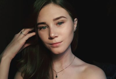 Close-up portrait of beautiful young woman over black background