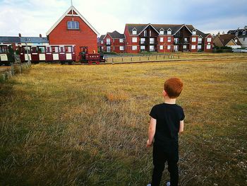 Rear view of boy standing on grassy field