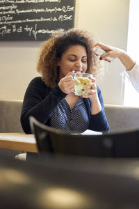 Young woman having drink while sitting at table