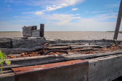 Abandoned metal structure on beach against sky