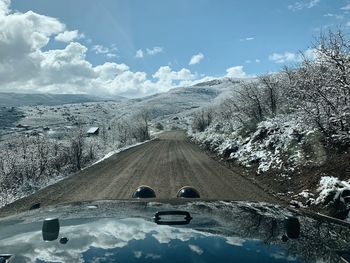 Road by snowcapped mountains against sky