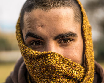 Close-up portrait of man covering face standing outdoors