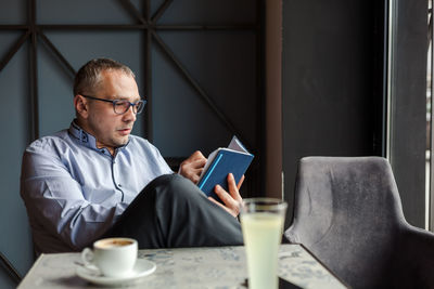 Midsection of man holding coffee while sitting at home