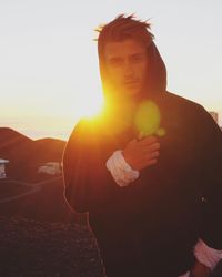 Young man standing against sky during sunset