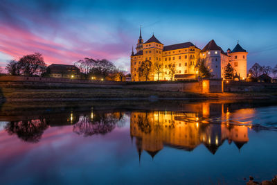 Reflection of illuminated buildings in lake at dusk