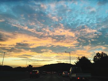 Cars on road against cloudy sky