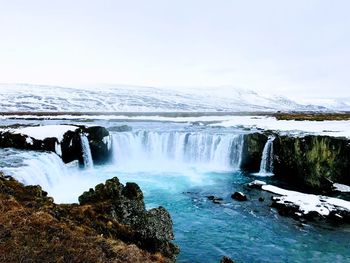 Scenic view of waterfall against sky during winter