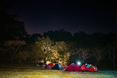 Tents on field against sky in forest at night