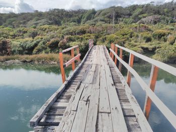 Footbridge over lake against sky