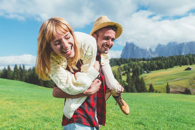 Happy friends standing on field against sky