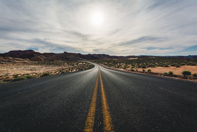 Road amidst field against sky