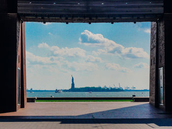 Statue of liberty and hudson river against sky in city seen through entrance