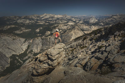 Rear view of woman climbing on mountain against sky