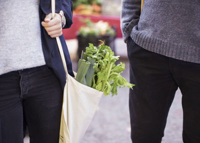 Midsection of couple with leafy vegetables outdoors