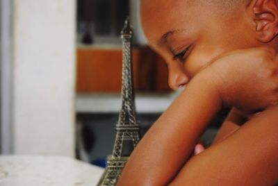 Close-up of boy by replica eiffel tower on table at home
