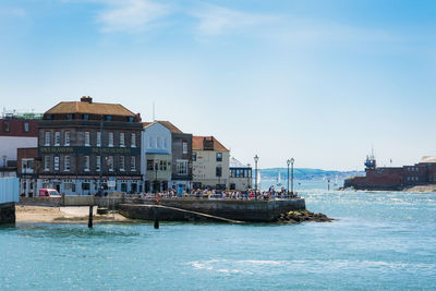 Buildings by sea against sky