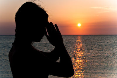 Silhouette woman at beach against sky during sunset