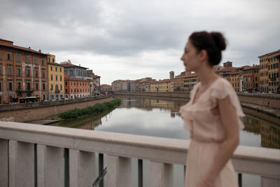 Woman standing by railing against river in city