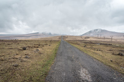 Road leading towards mountains against sky