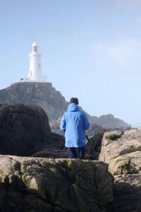 Rear view of a man with light house against blue sky