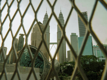 Panoramic shot of buildings seen through chainlink fence