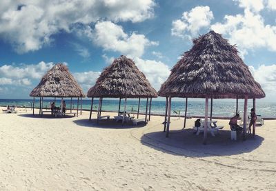 Deck chairs on beach against sky