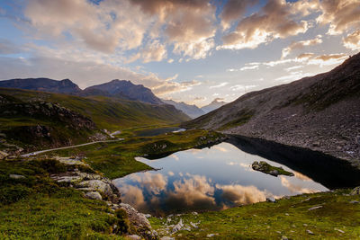 Scenic view of lake by mountains against cloudy sky at gran paradiso national park