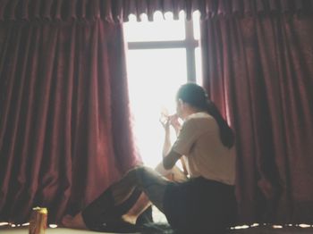 Side view of woman looking through window