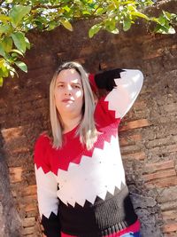 Portrait of beautiful young woman standing against brick wall