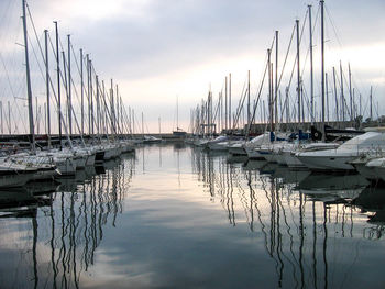 Boats moored in harbor at sunset