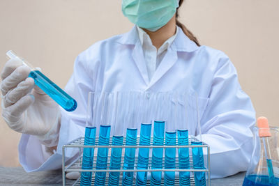 Midsection of scientist holding test tubes against white background