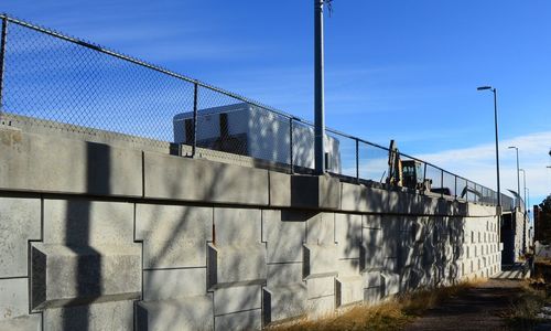 Fence on wall against blue sky