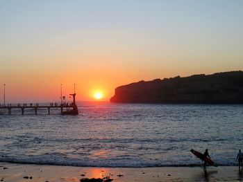 Silhouette person on beach against sky during sunset