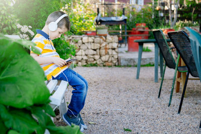 Cute boy listening music while using mobile phone at cafe