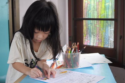 Girl coloring on paper at home
