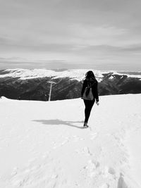 Full length rear view of man walking on snow covered landscape