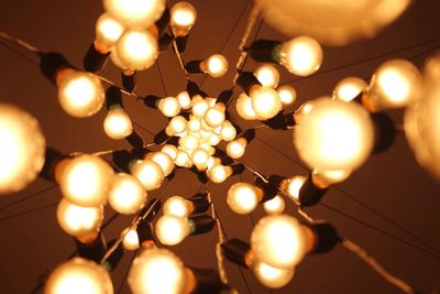 Close-up of lit light bulb at night